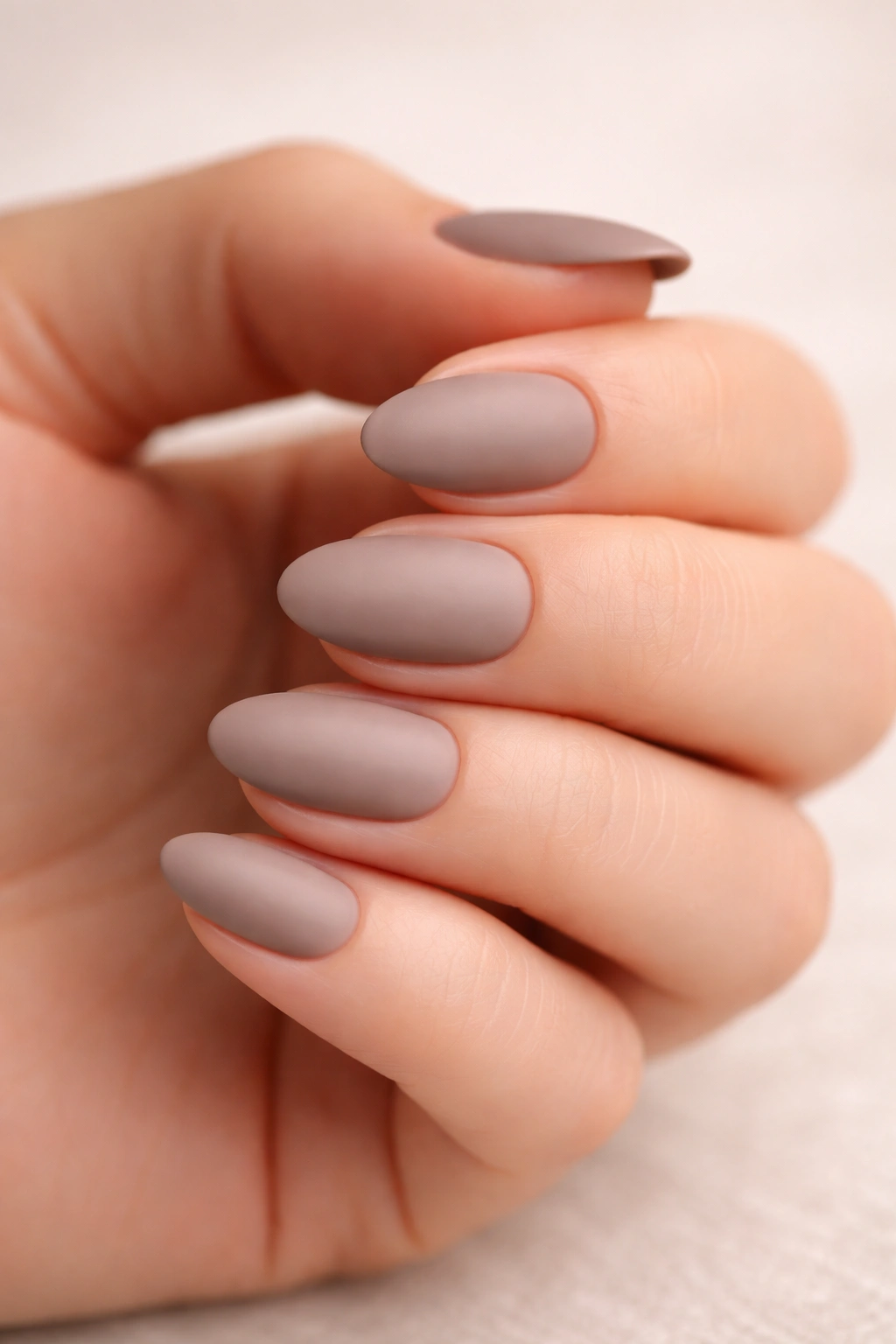 Close-up of matte taupe short almond nails with velvety texture