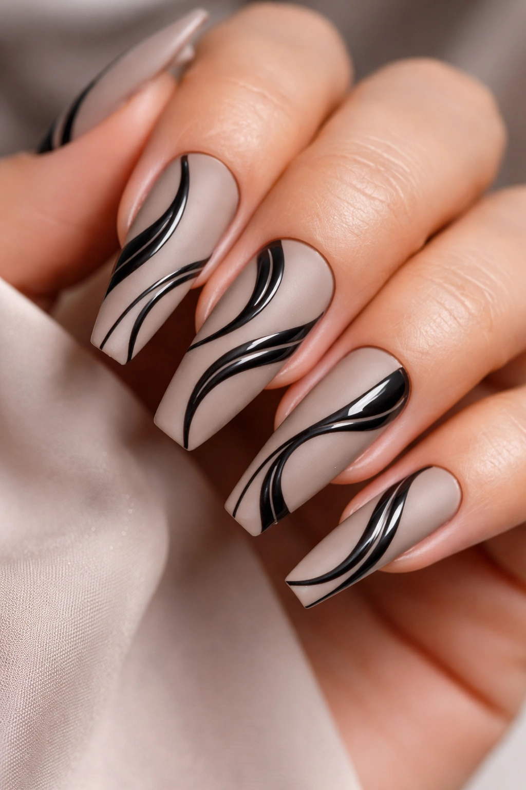 Matte taupe nails with glossy black swirl designs on ballerina shape