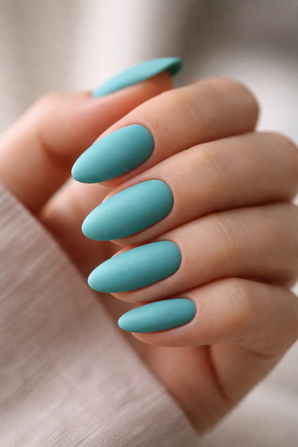Close-up of short almond nails in matte turquoise finish