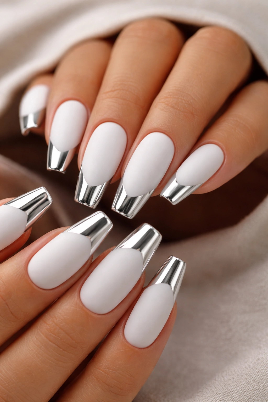 Close-up of matte white nails with chrome metallic tips, showing contrast between finishes.