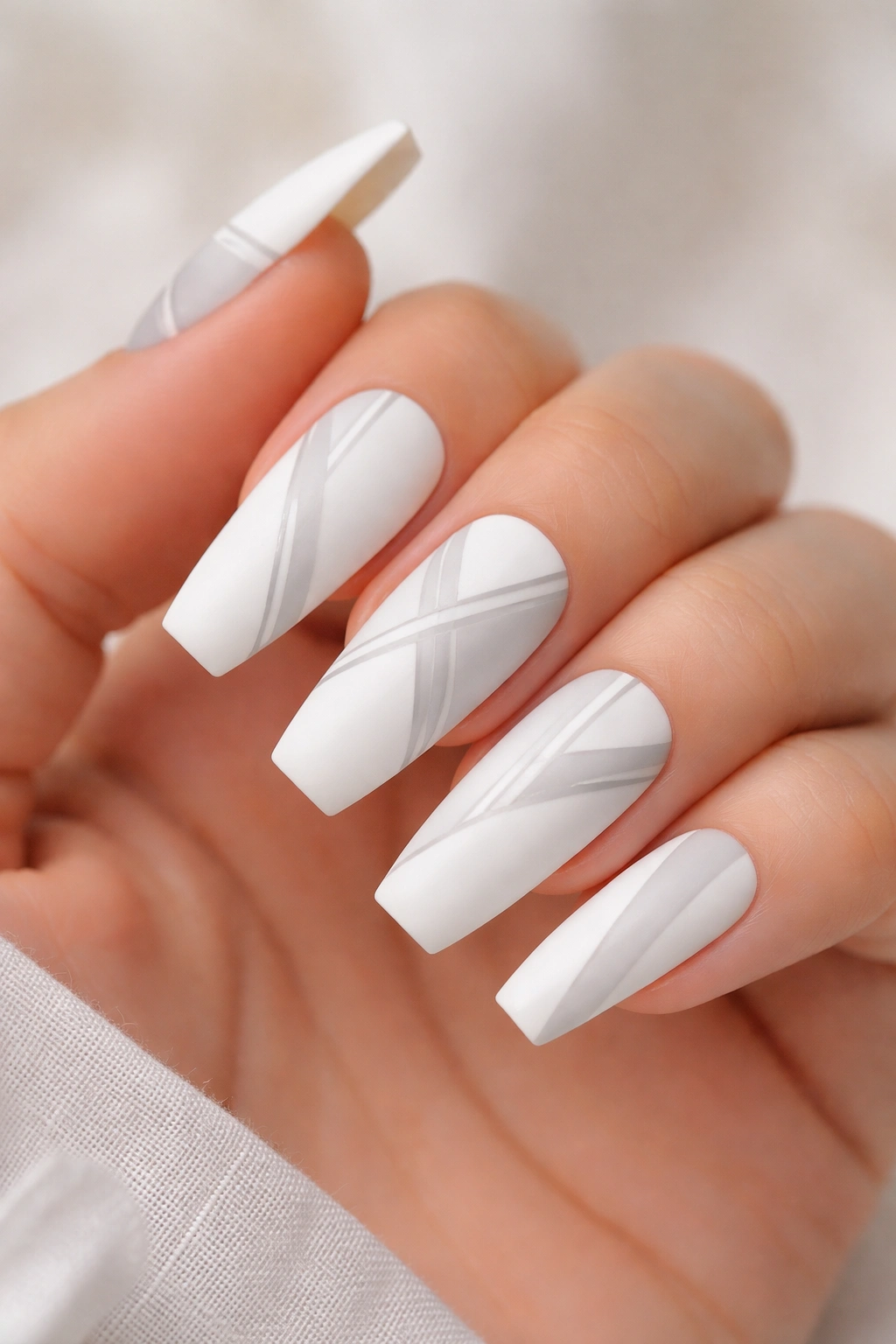 Matte white coffin nails with geometric patterns on neutral background