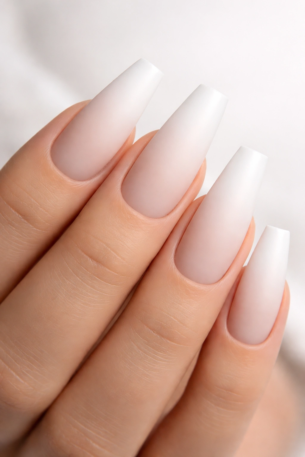 Close-up of matte white ombre nails on coffin shape