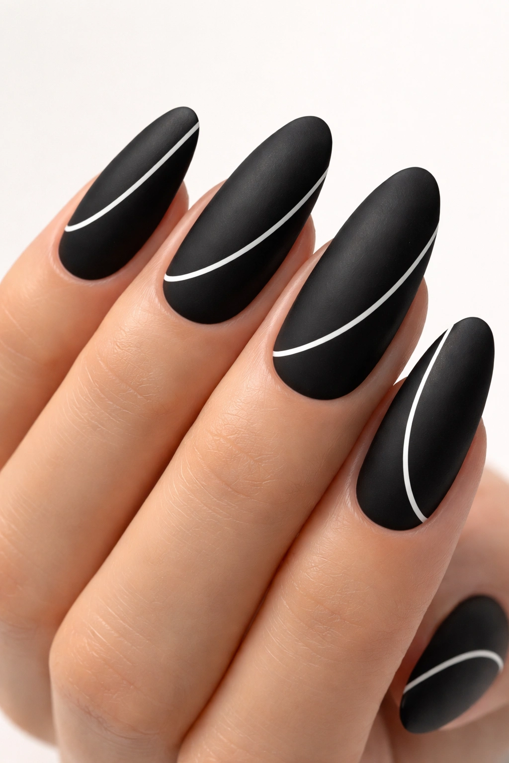 Matte black nails with white negative-space lines on long oval nails