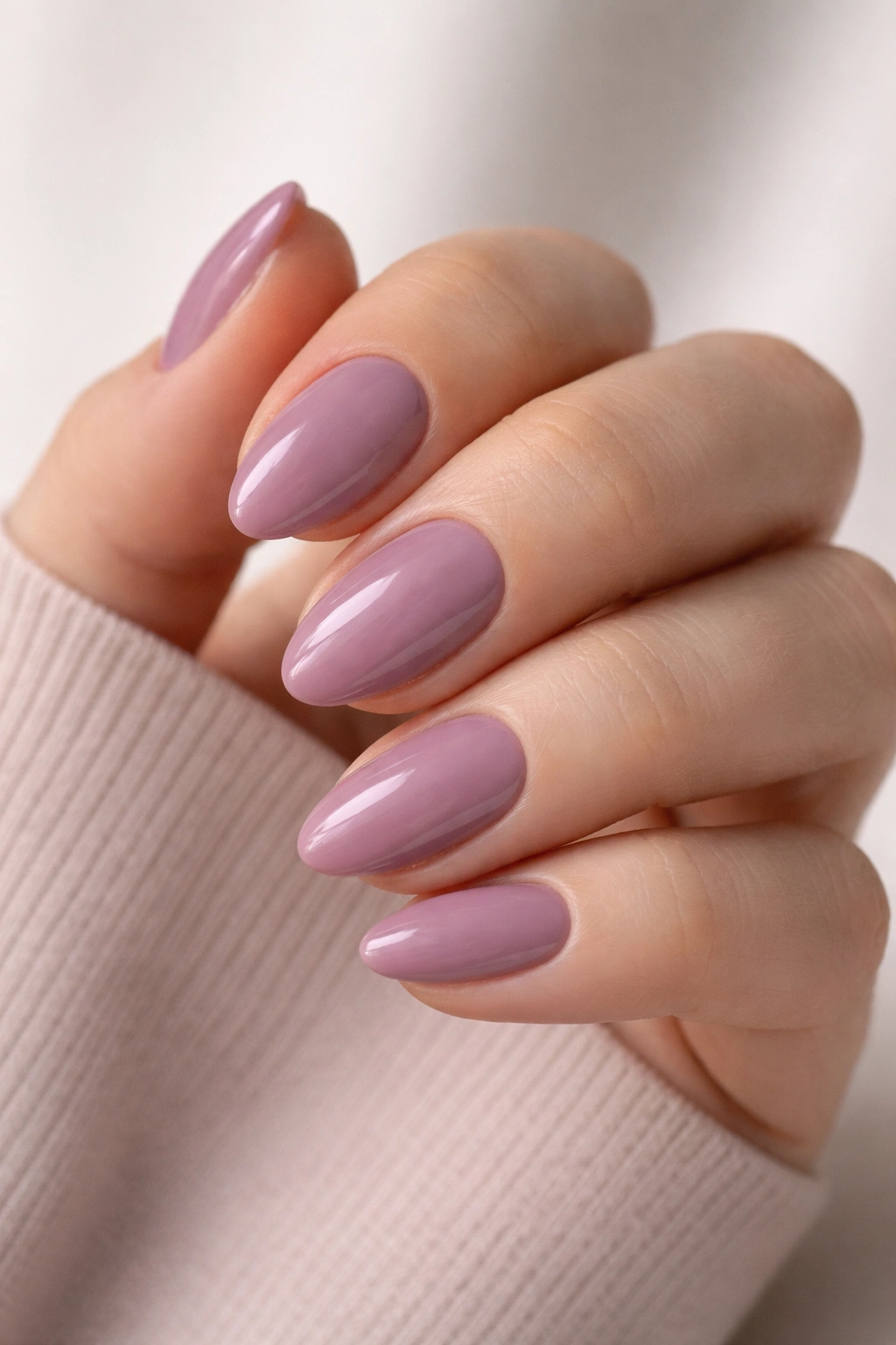 Close-up of soft mauve almond polygel nails on a short shape with glossy finish