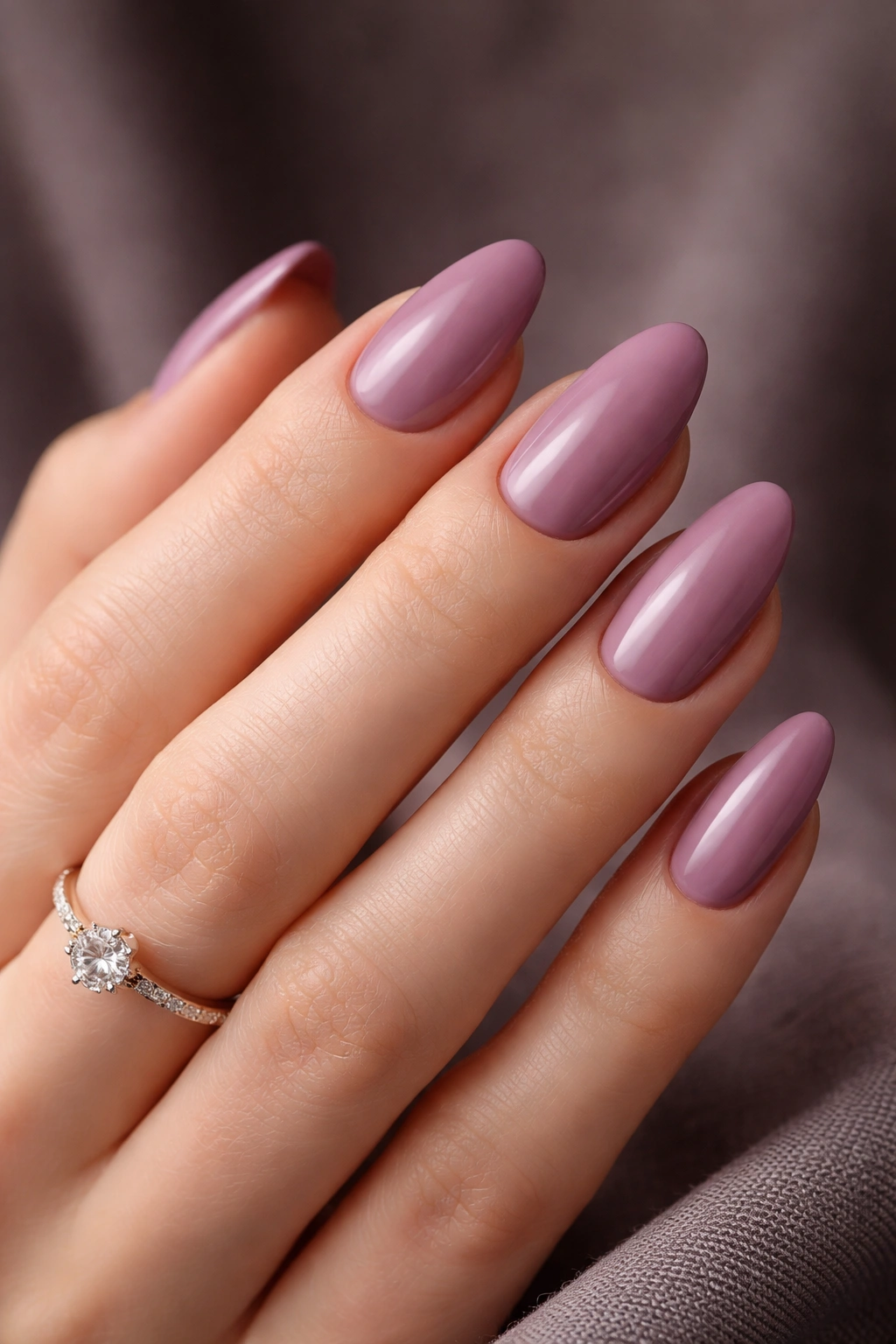 Close-up of hand with elegant mauve nails in moody studio lighting