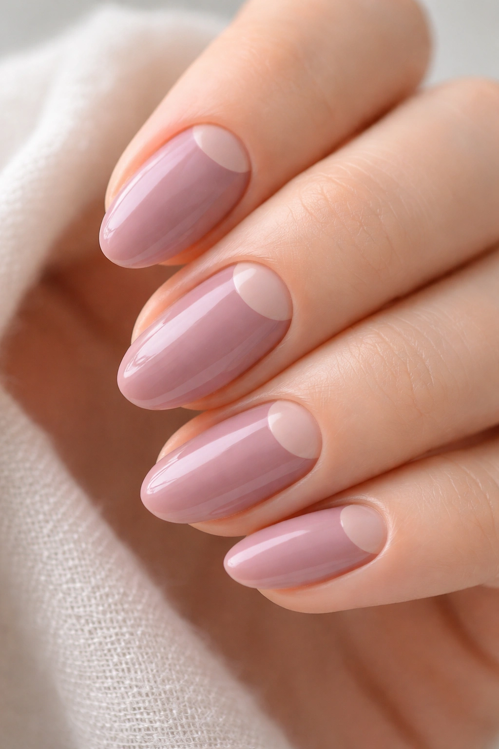 Close-up of short mauve almond nails showing a crescent negative-space cutout near the cuticle