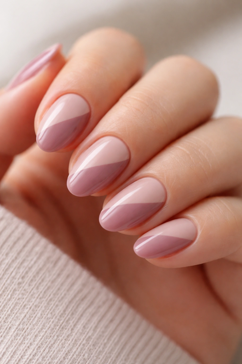 Close-up of short almond nails with diagonal mauve and nude color block design
