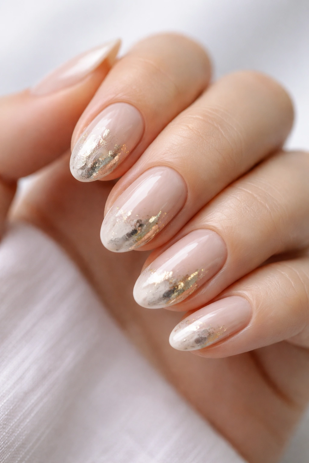 Close-up of short almond nails with smudged metallic gold accents.