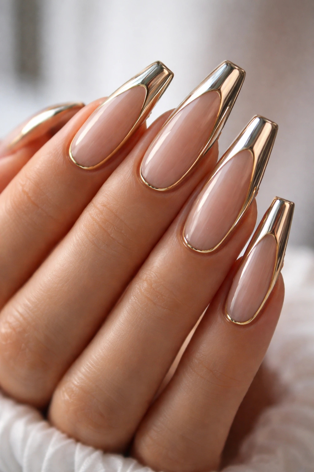 Close-up of coffin nails with gold and chrome metallic accents on a bare hand