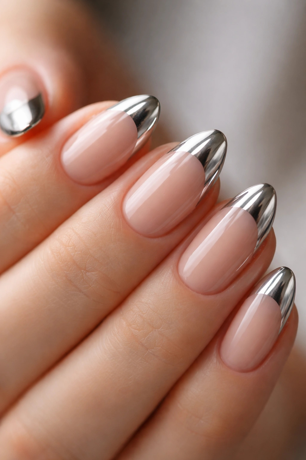 Close-up of short almond nails with metallic chrome tips
