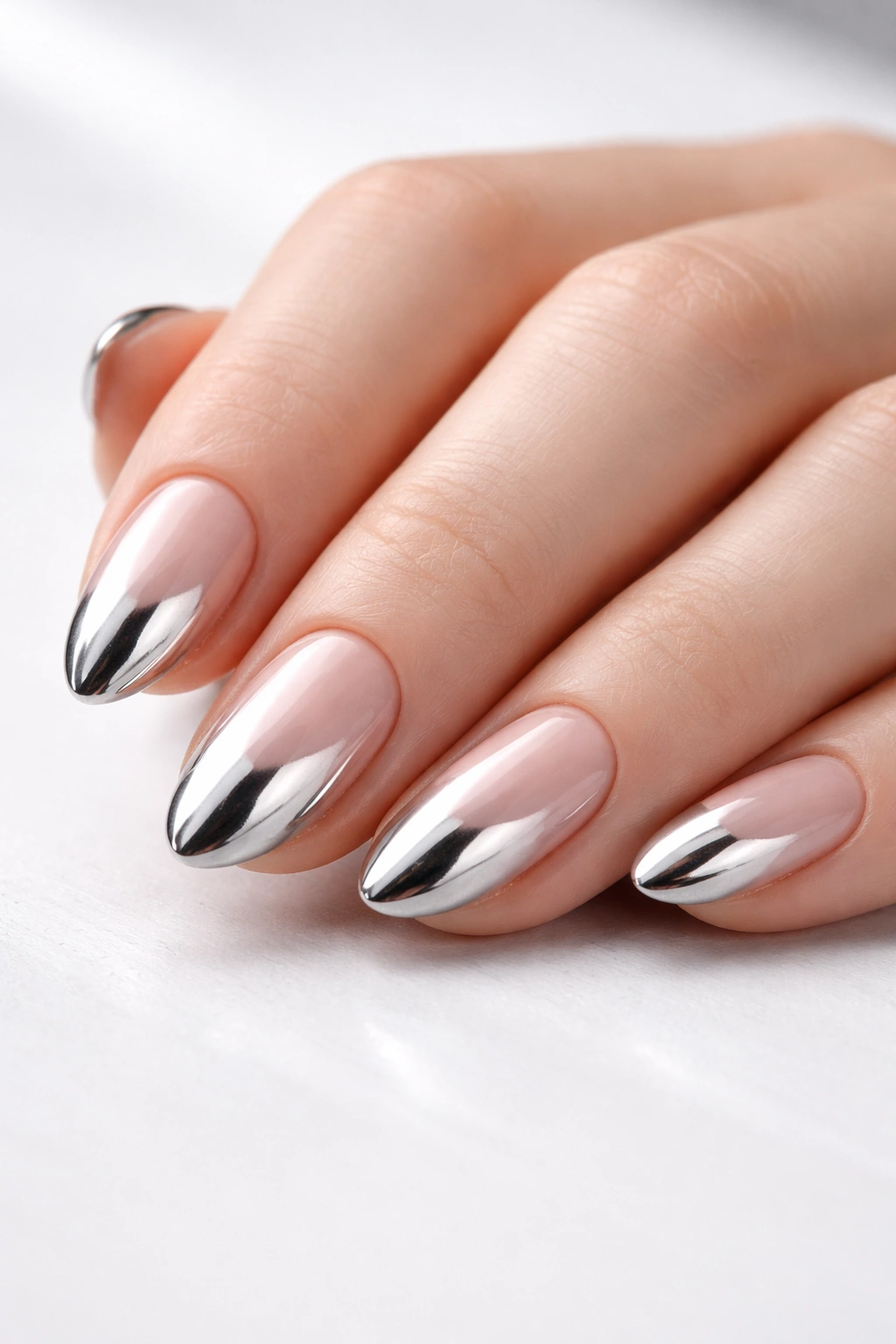 Close-up of short almond nails with metallic silver finish and mirror-like shine.