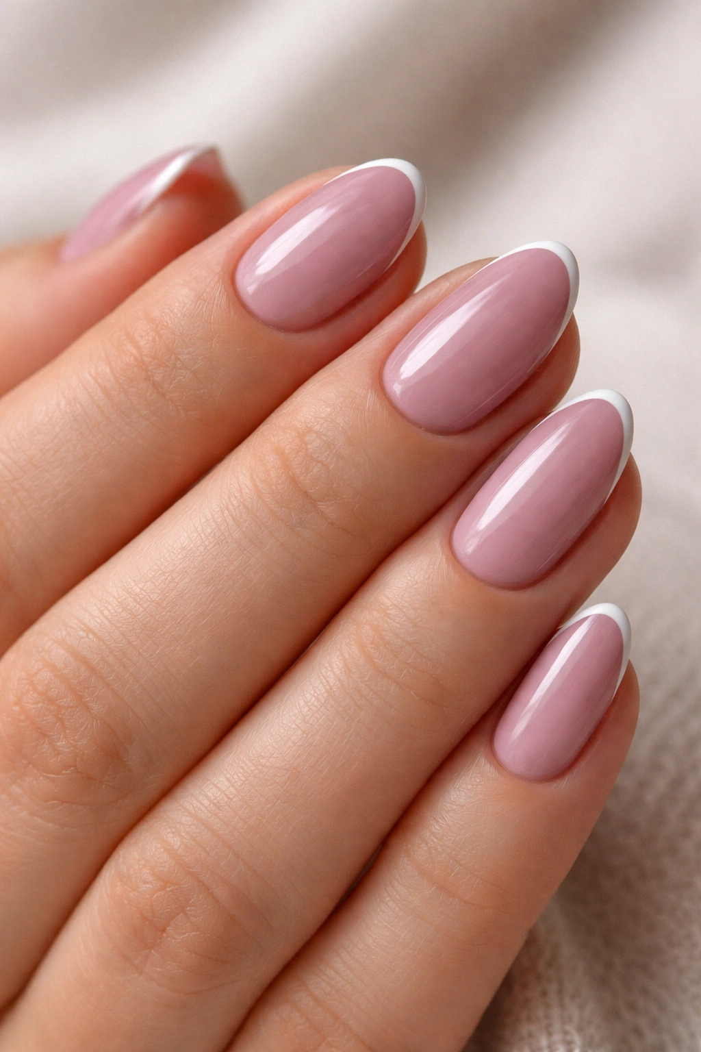 Close-up of short almond nails with mauve base and tiny white edge French tips