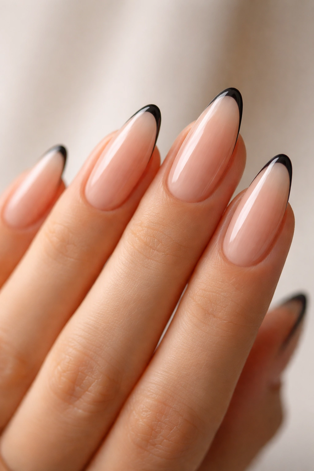 Close-up of almond nails with ultra-thin black micro French tips on nude base