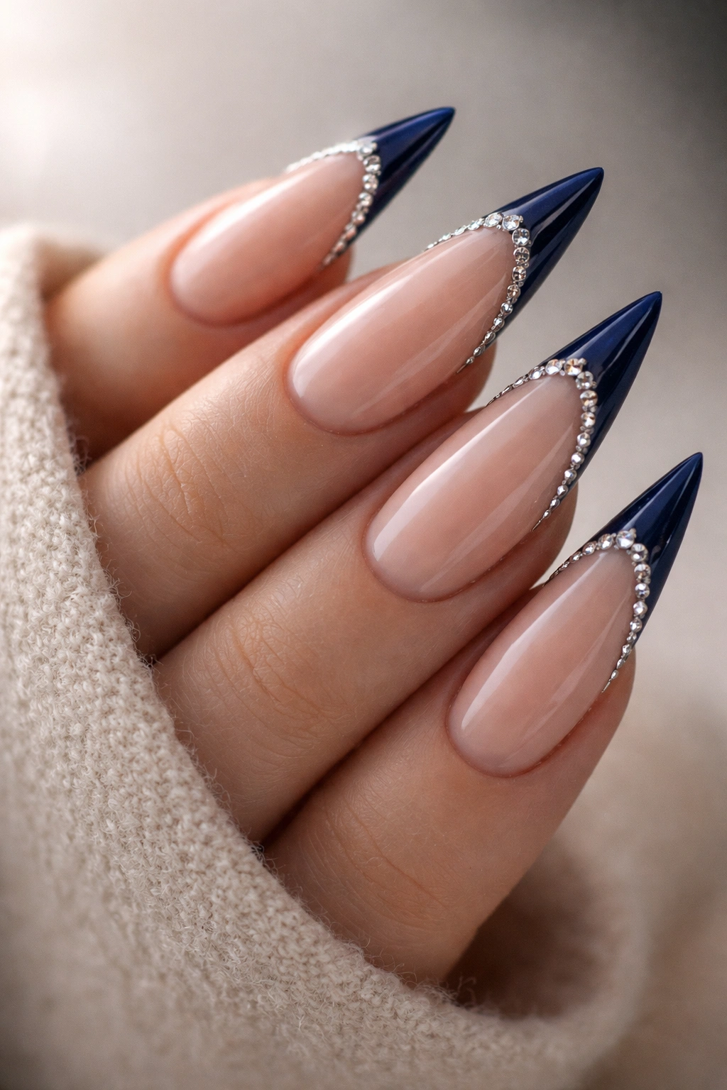 Stiletto nails with midnight blue French tips and rhinestones