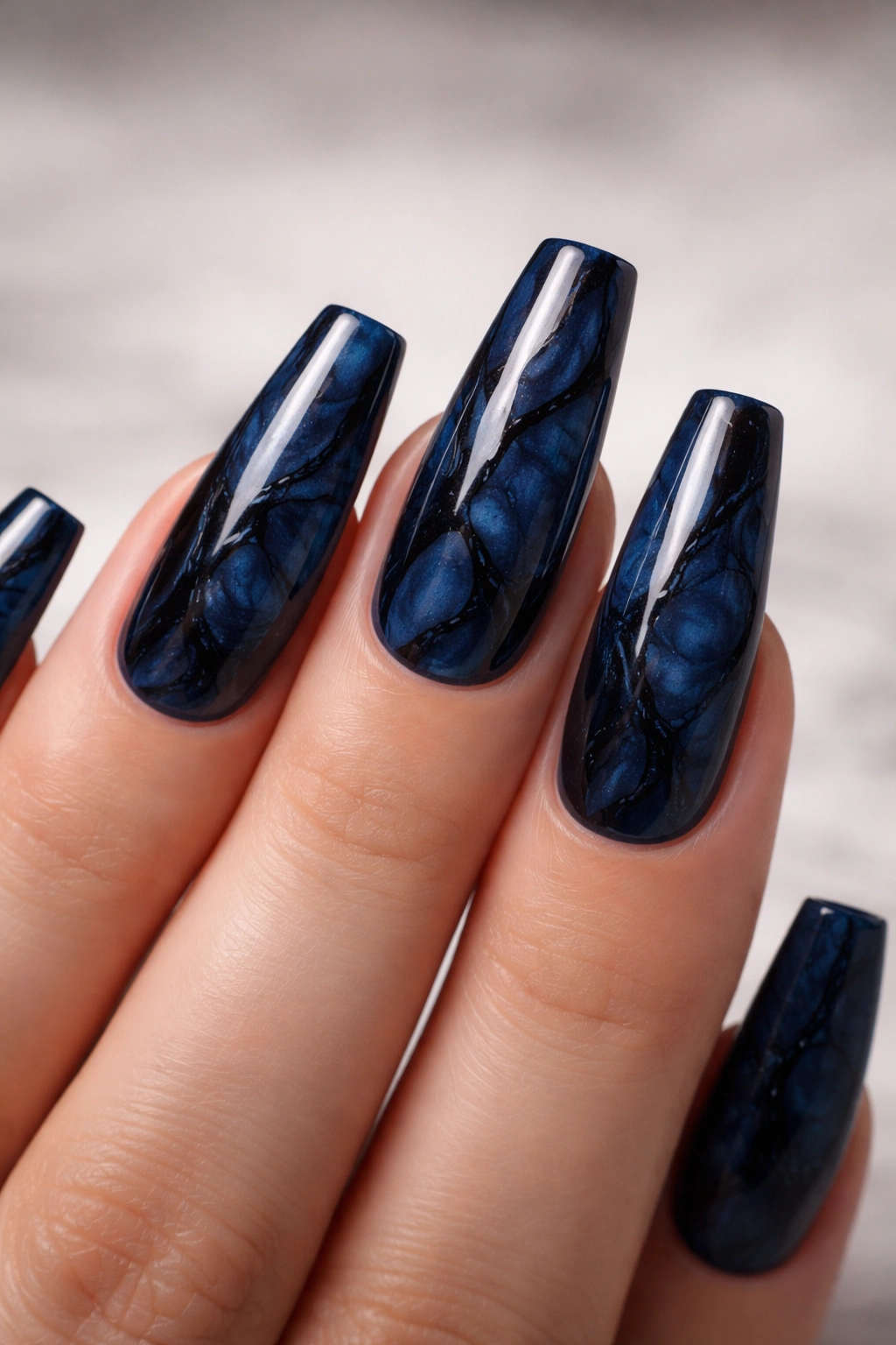Midnight blue marble coffin nails with black swirls on long nails.