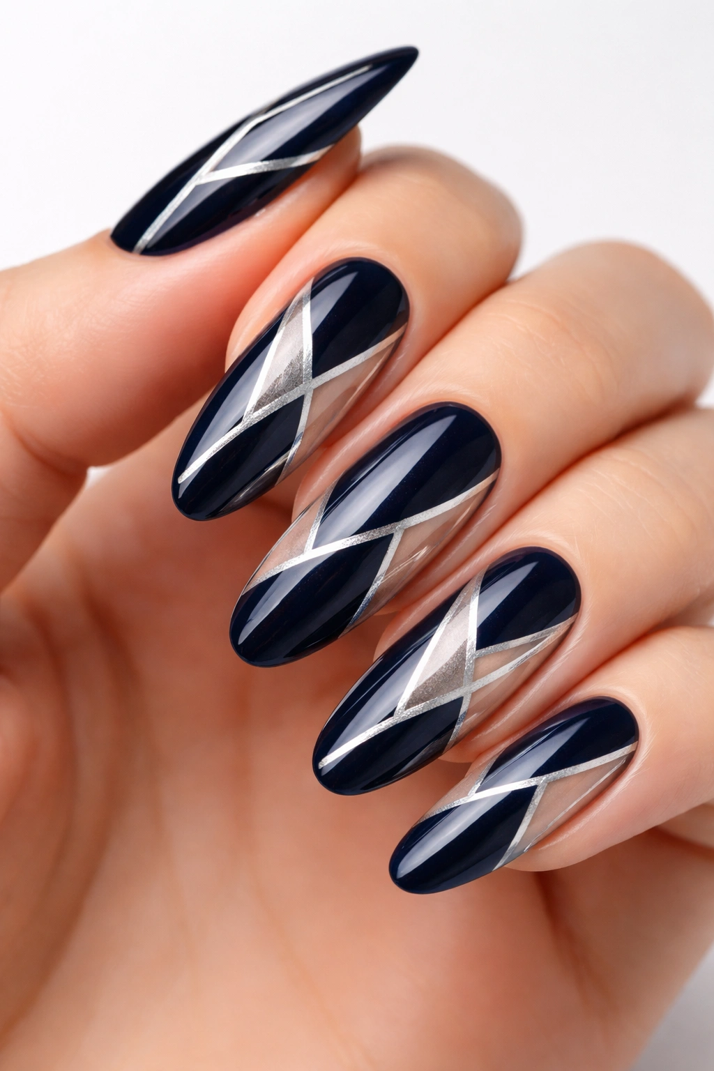 Close-up of long oval nails in midnight blue with silver geometric negative-space shapes