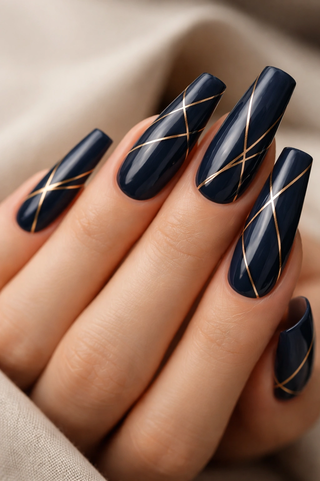 Close-up of midnight blue coffin nails with thin gold geometric lines