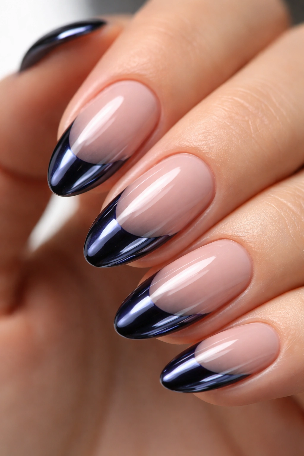 Close-up of a short almond nail showing a chrome-tipped navy tip reflecting light