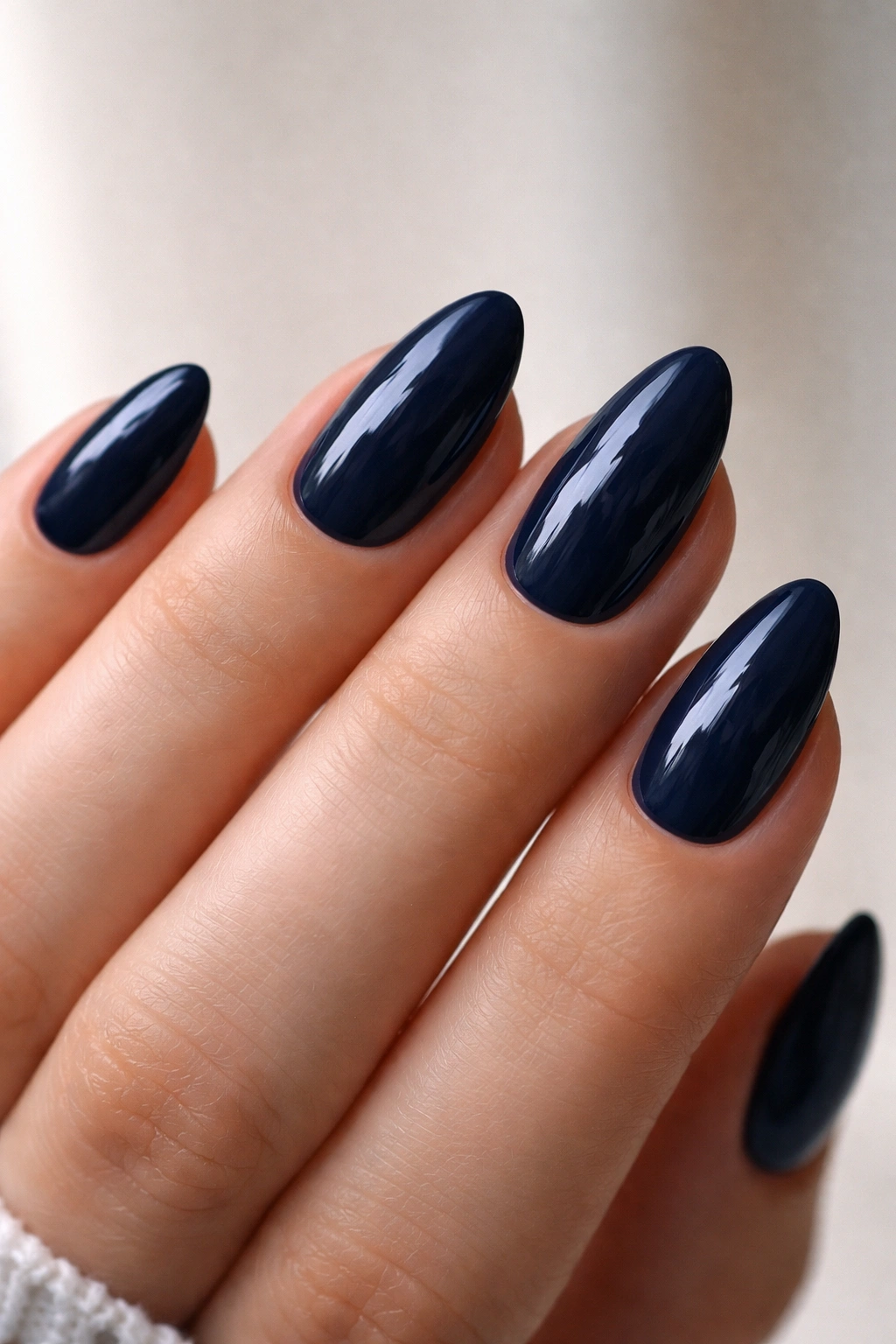 Close-up of midnight navy almond nails on a hand