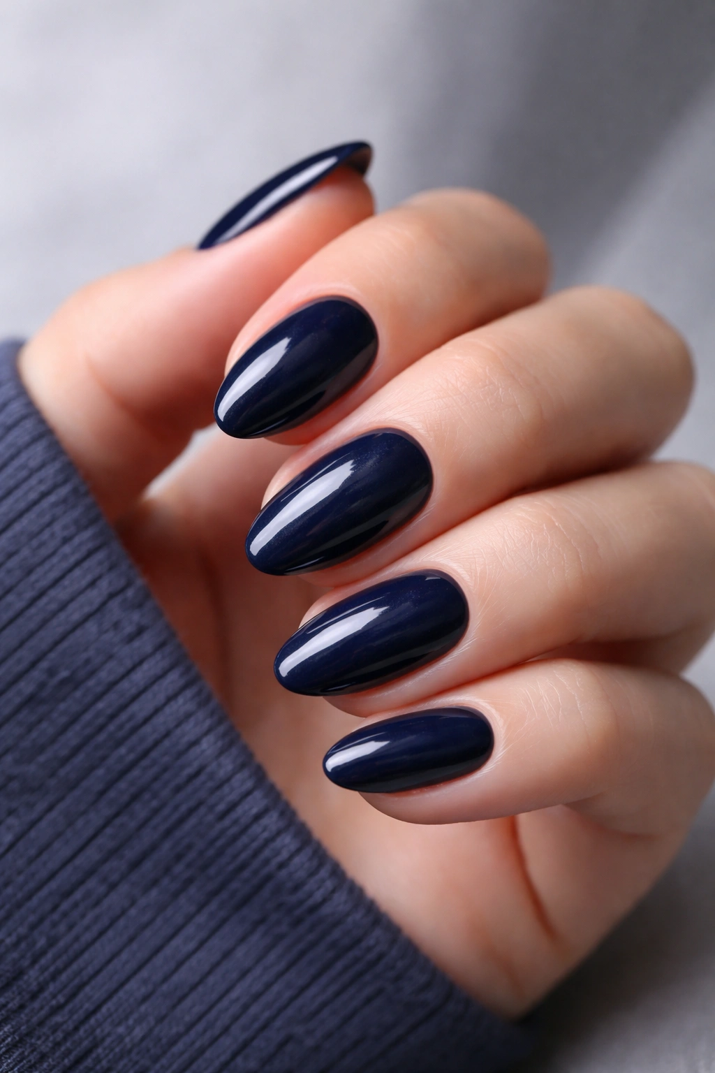 Close-up of short almond nails in midnight navy with high-gloss finish