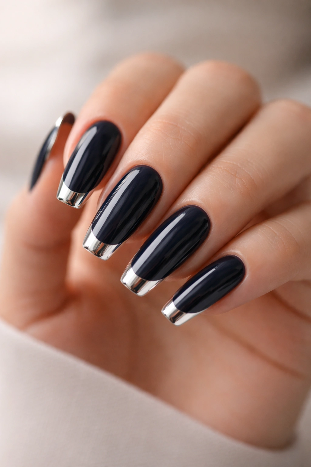 Midnight navy nails with silver mirror tips on a neutral background