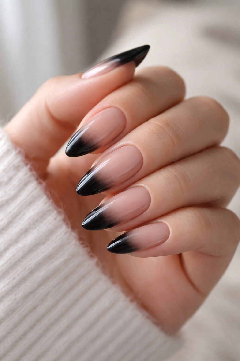 Almond nails with black French ombre tips fading into a sheer base, glossy finish