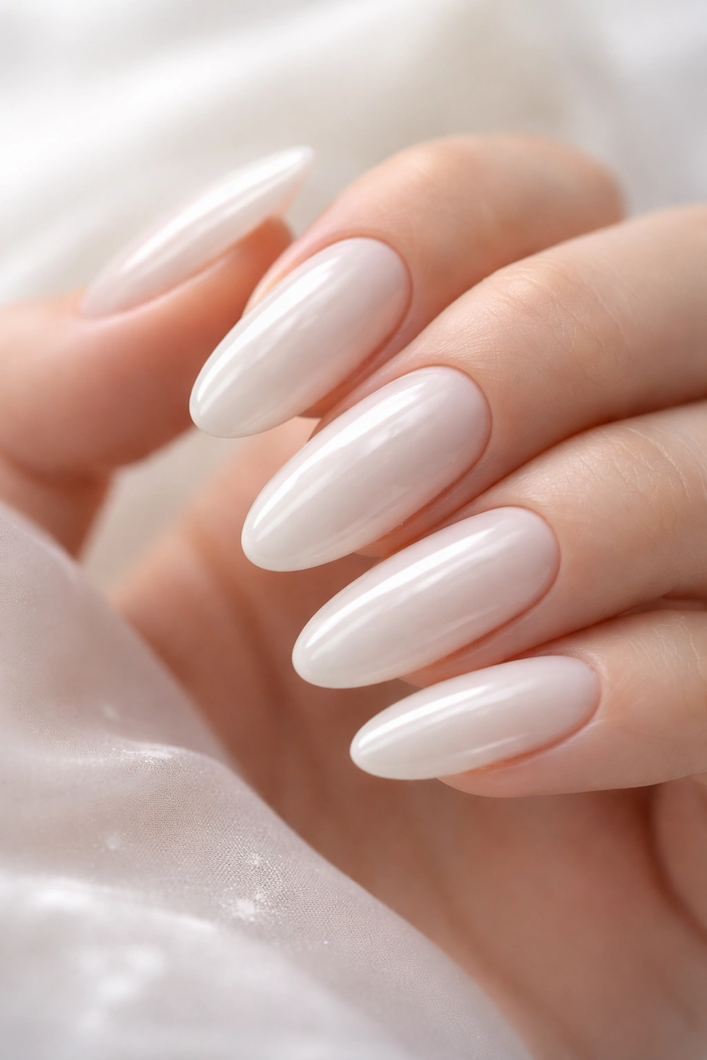 Close-up of long oval nails with creamy pearl white milk bath finish
