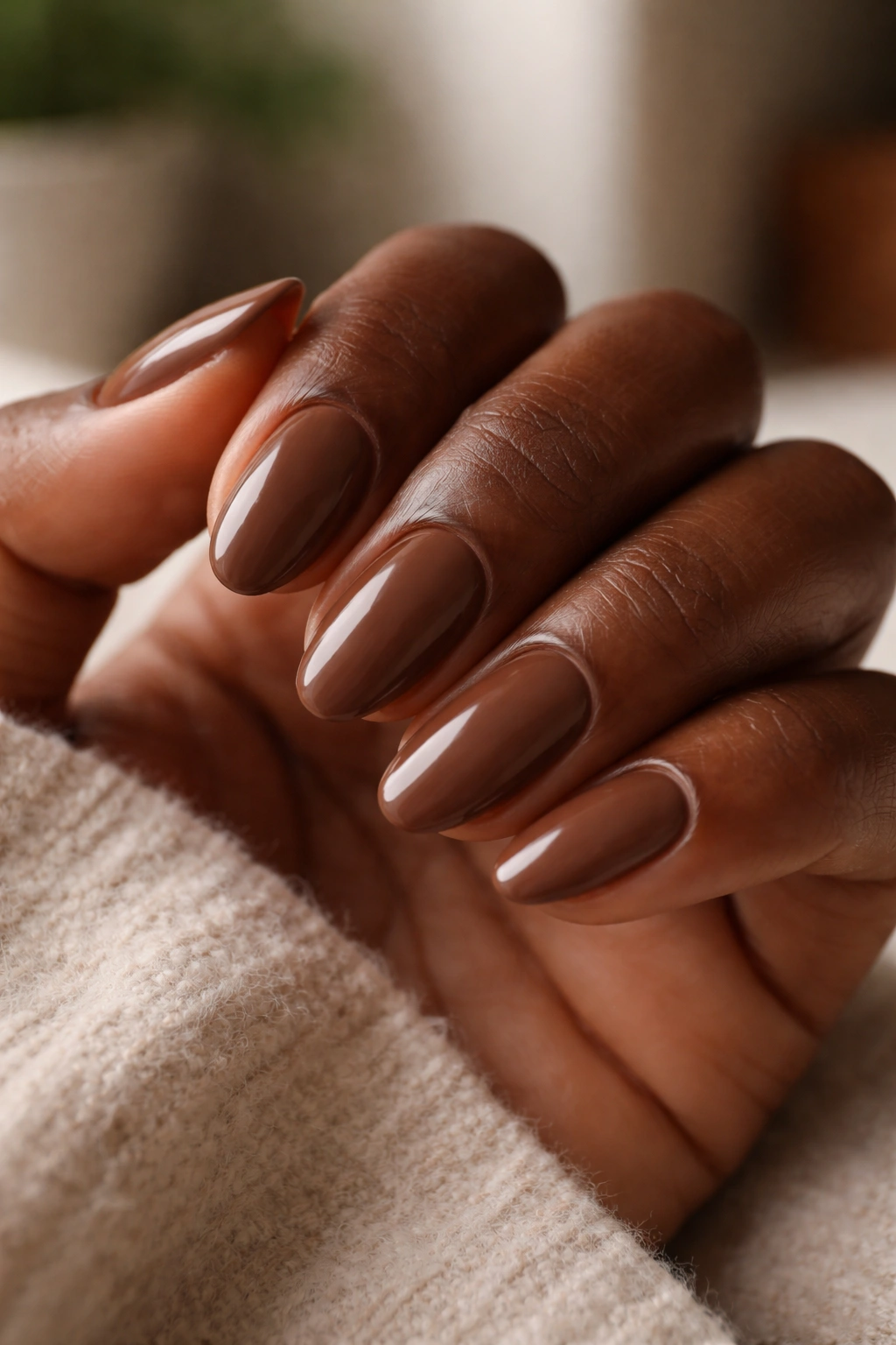 Close-up of short almond nails in milk chocolate brown on dark skin with smooth finish