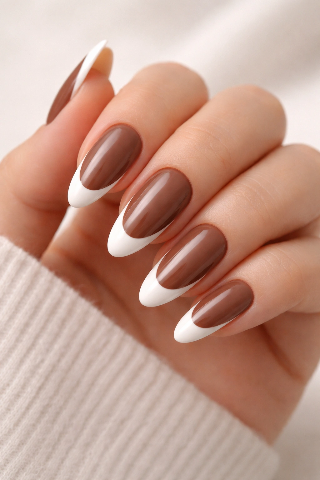 Close-up of milk chocolate brown French manicure with white tips on almond nails.