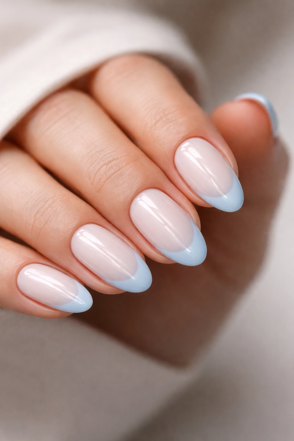Close-up of short almond nails with milky base and powder blue tips