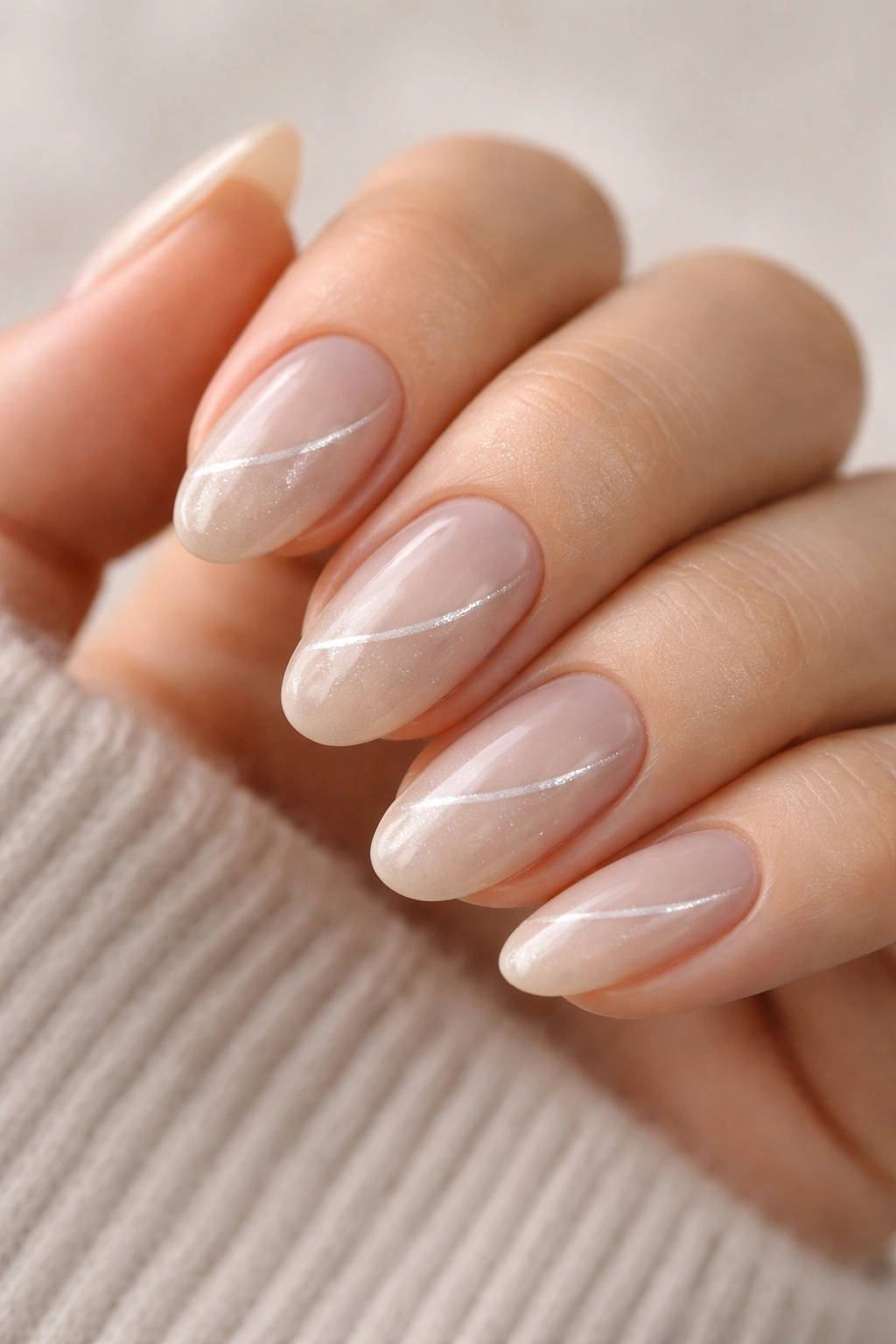 Close-up of short almond nails in milky beige with silver cat-eye line