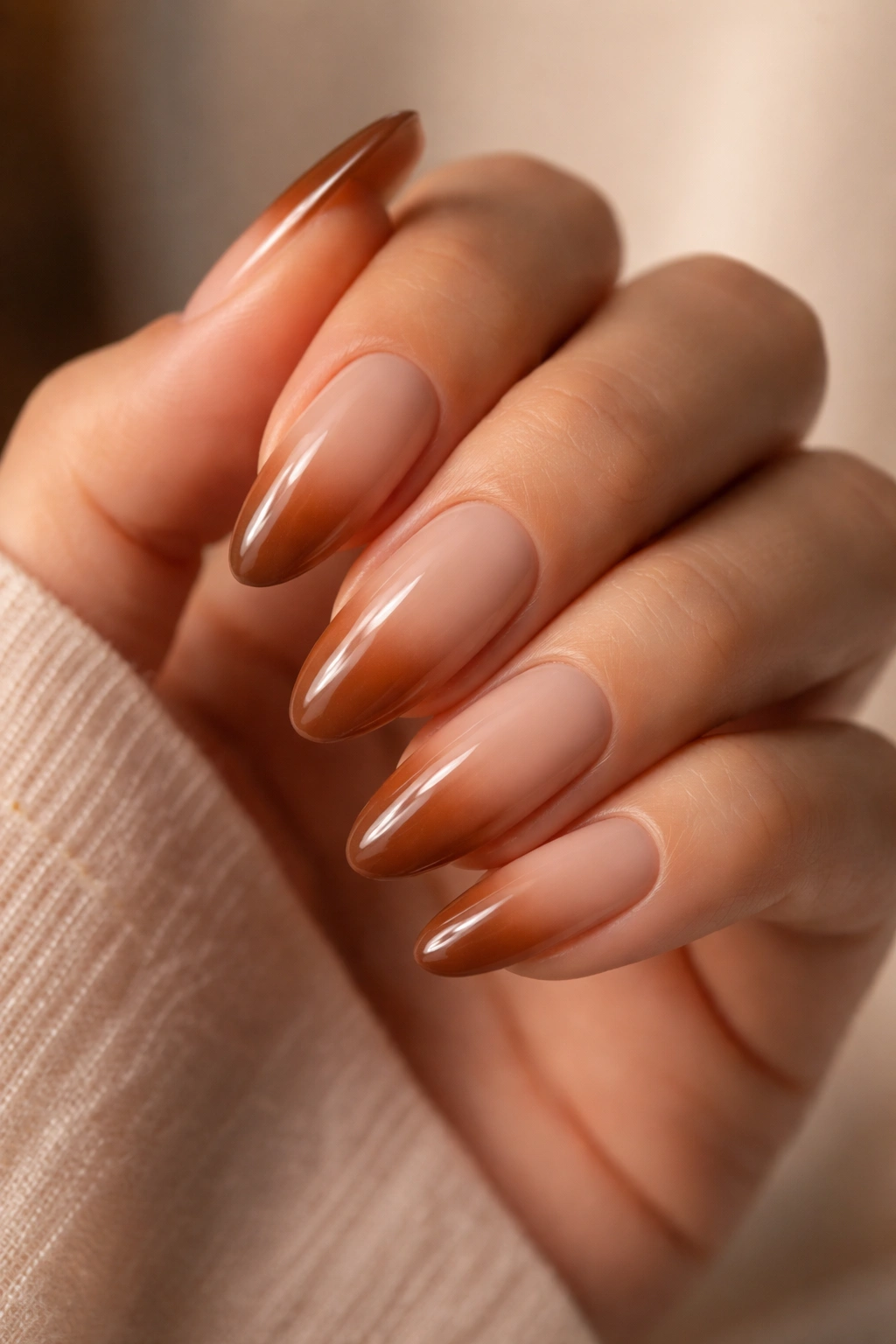 Long oval nails with milky beige to cinnamon brown gradient in warm light