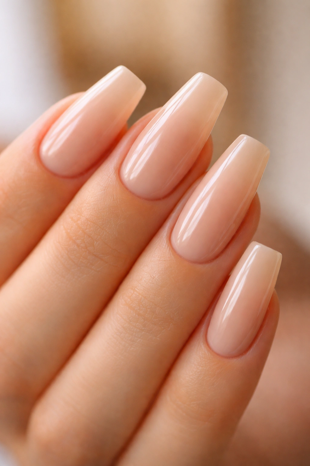 Milky beige nails with glossy top coat on medium-length ballerina nails