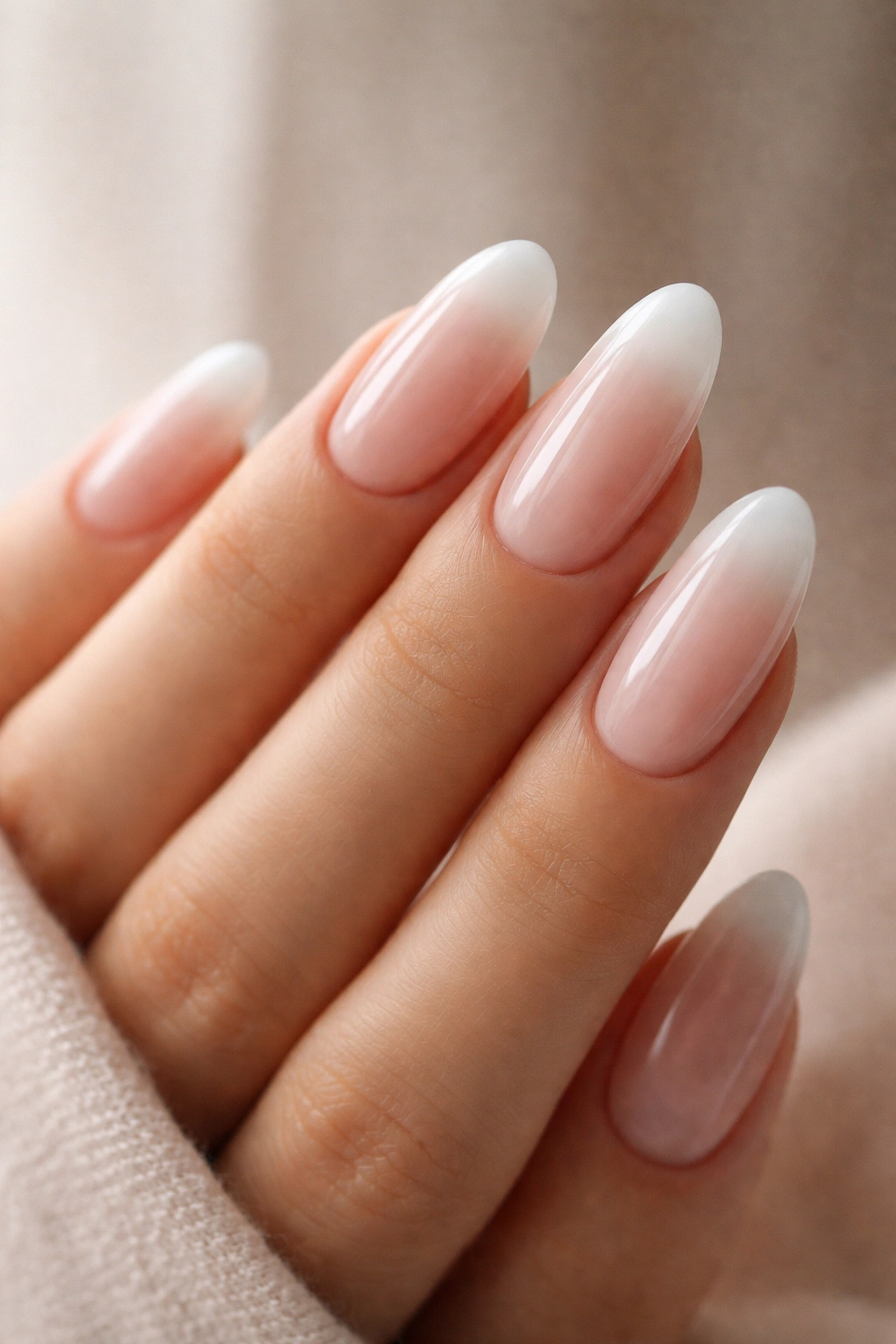 Close-up of milky french tips on long oval nails with blurred edges