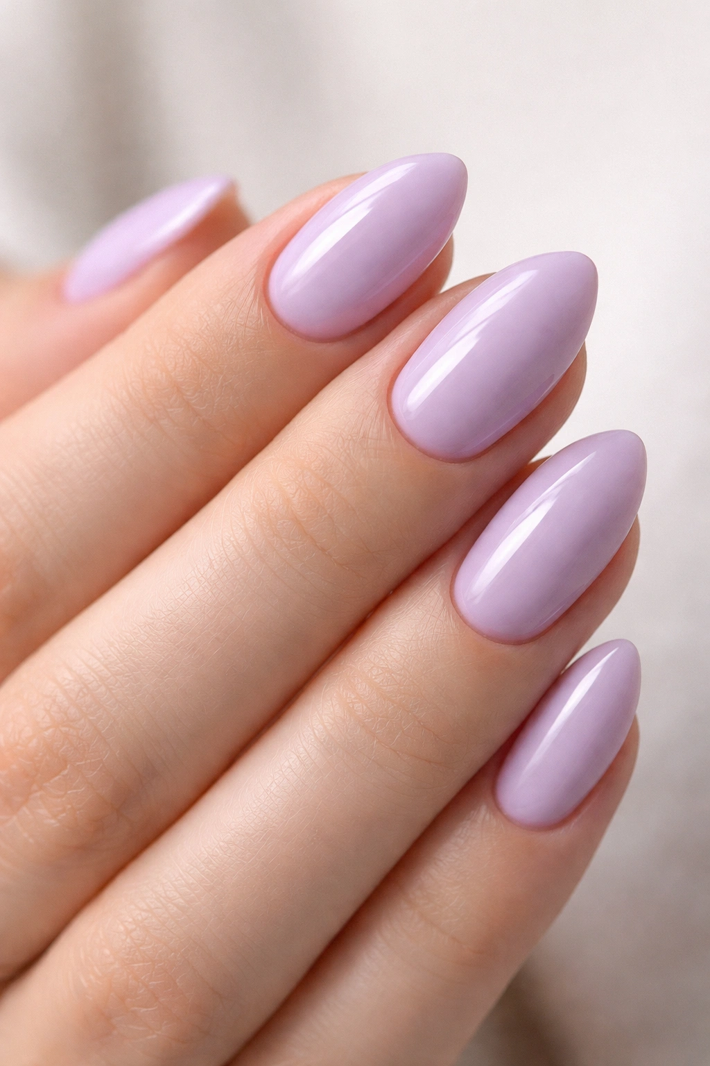 Close-up of short almond nails painted milky lavender with glossy finish