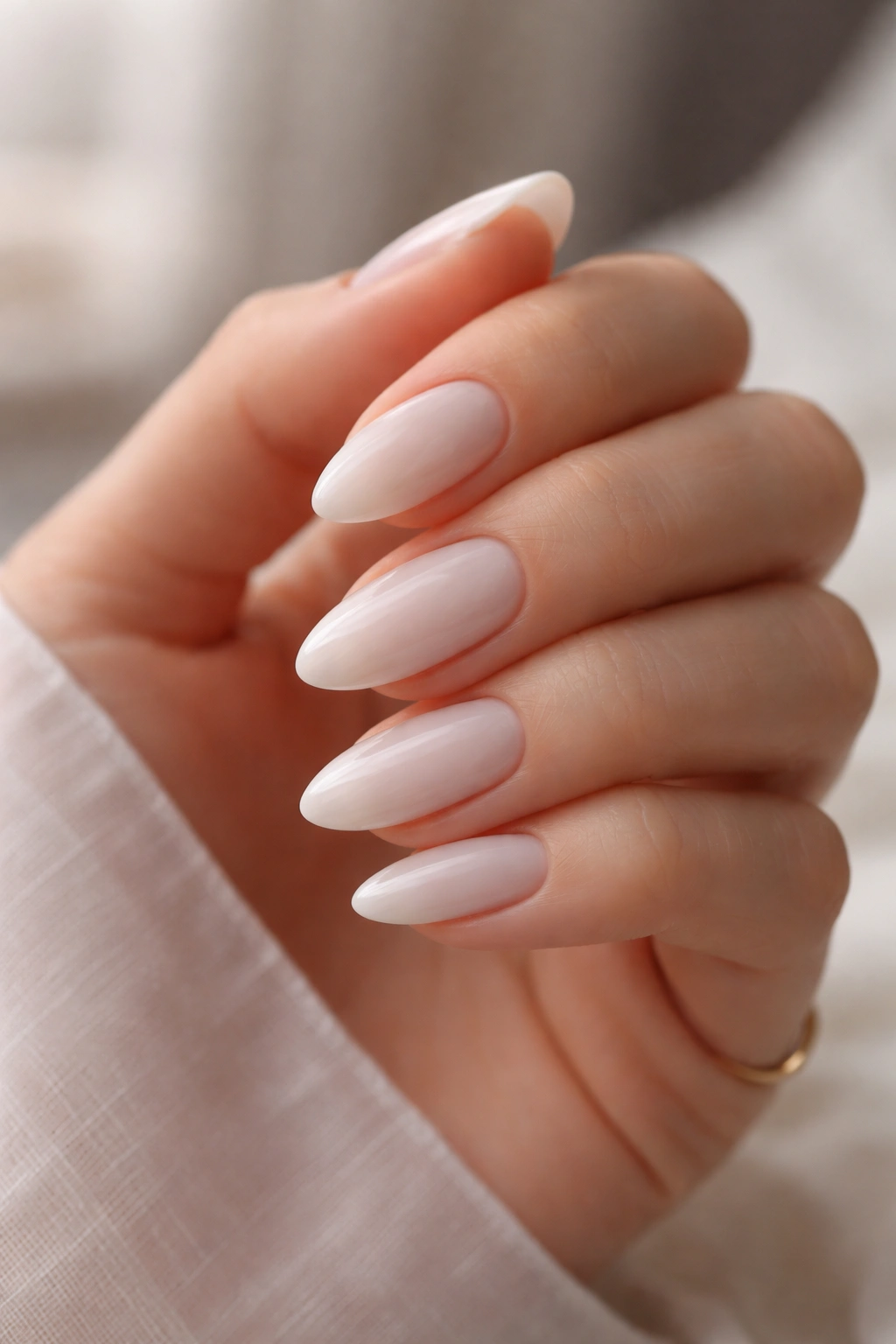 Close-up of milky white almond nails on a hand with a clean background