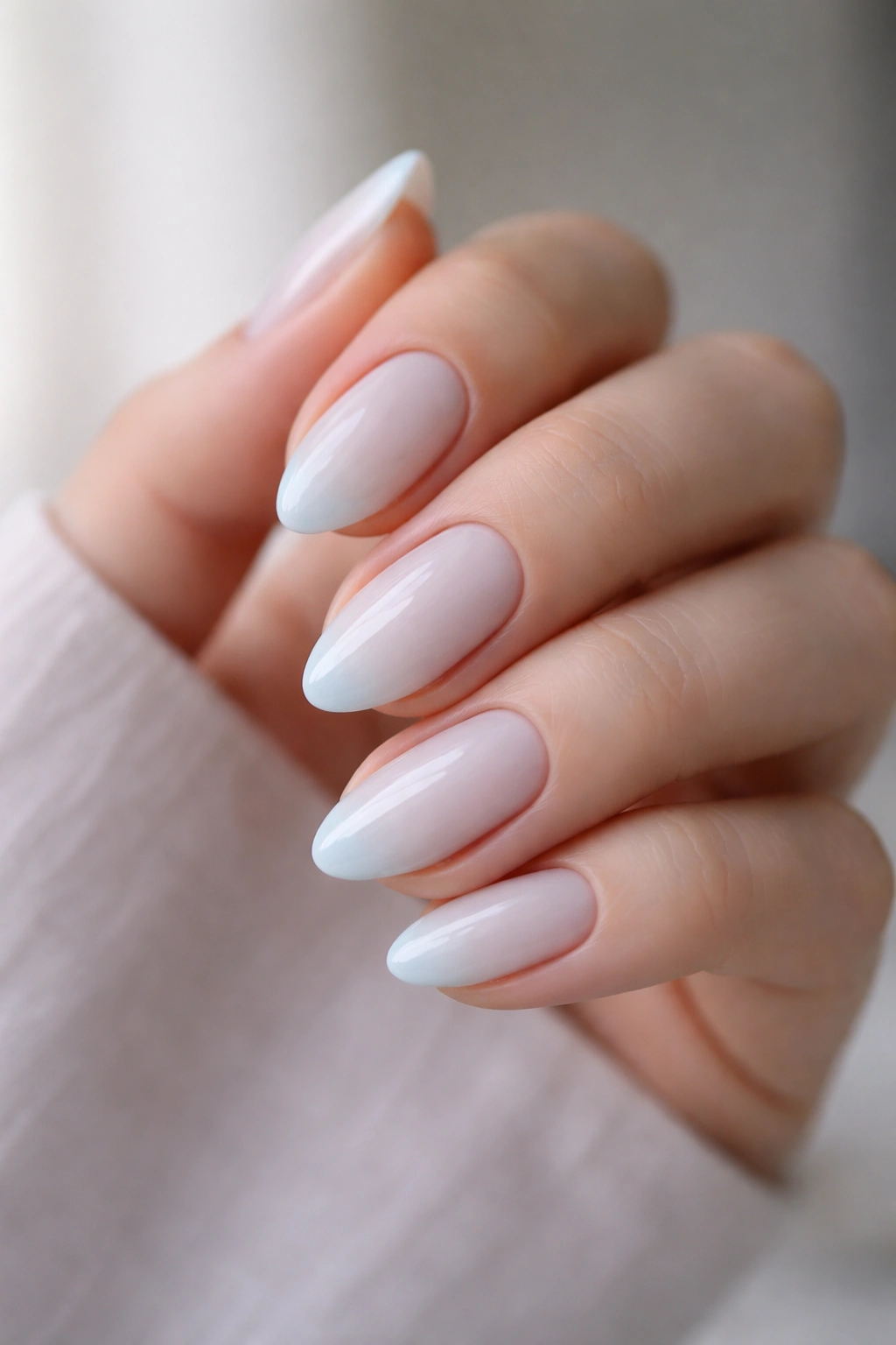 Close-up of blue-tinted milky almond nails on a hand