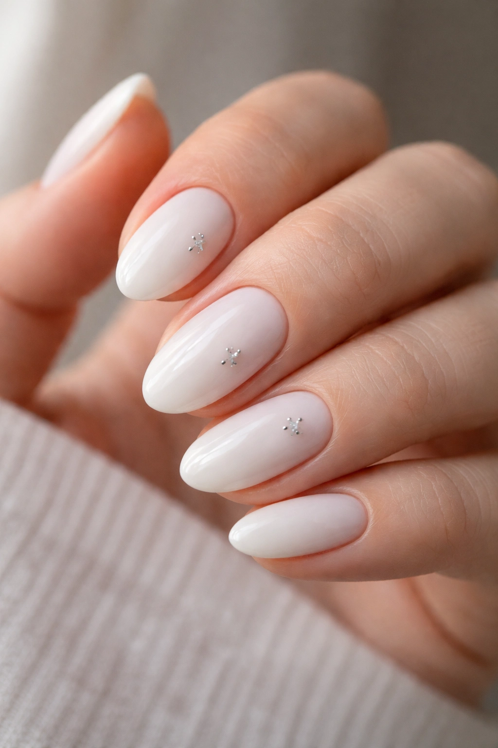 Almond nails with tiny silver star accents on milky white base