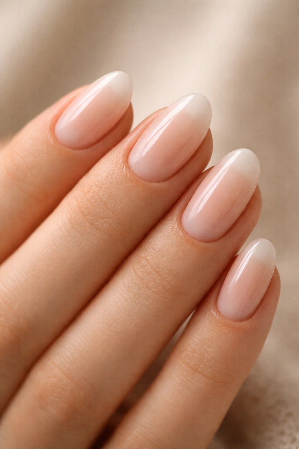 Close-up of short almond nails with milky nude tips blending softly into base