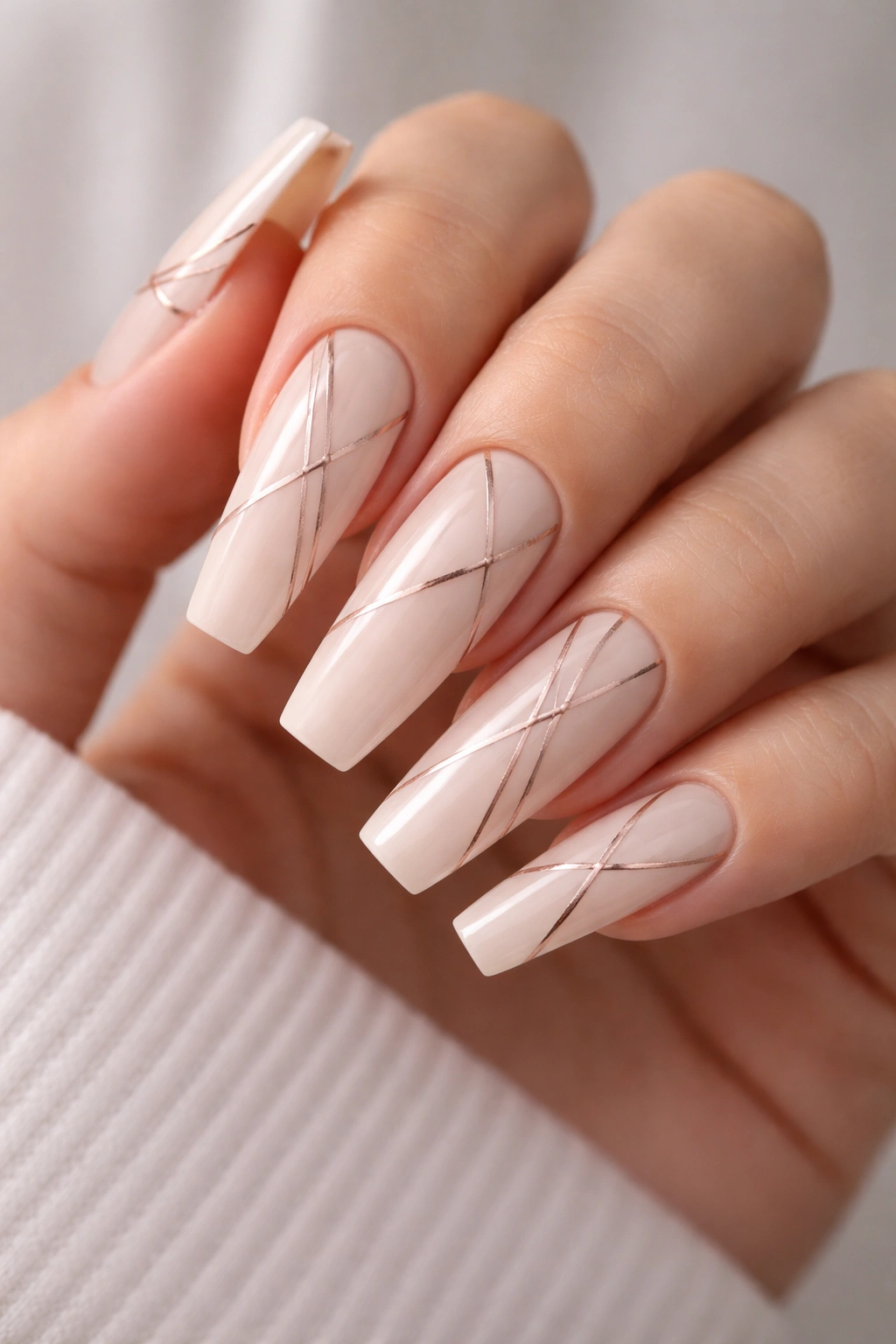 Close-up of milky nude coffin nails with delicate geometric line work