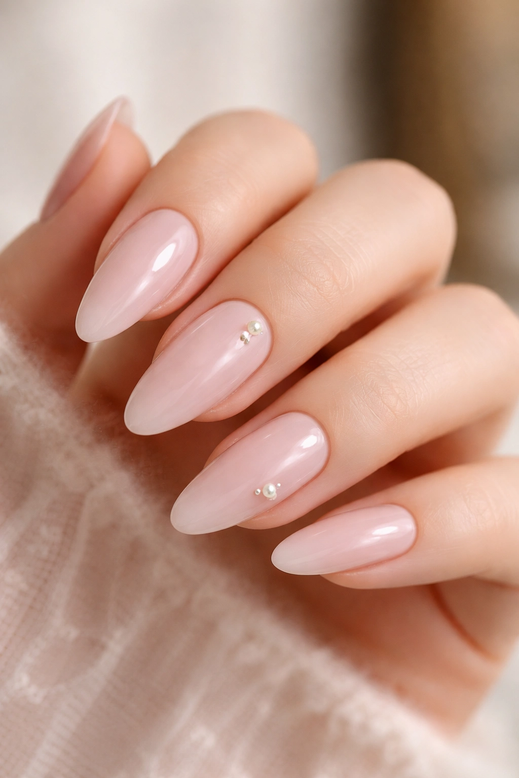 Almond nails in milky pink with tiny pearl accents on a couple of nails.