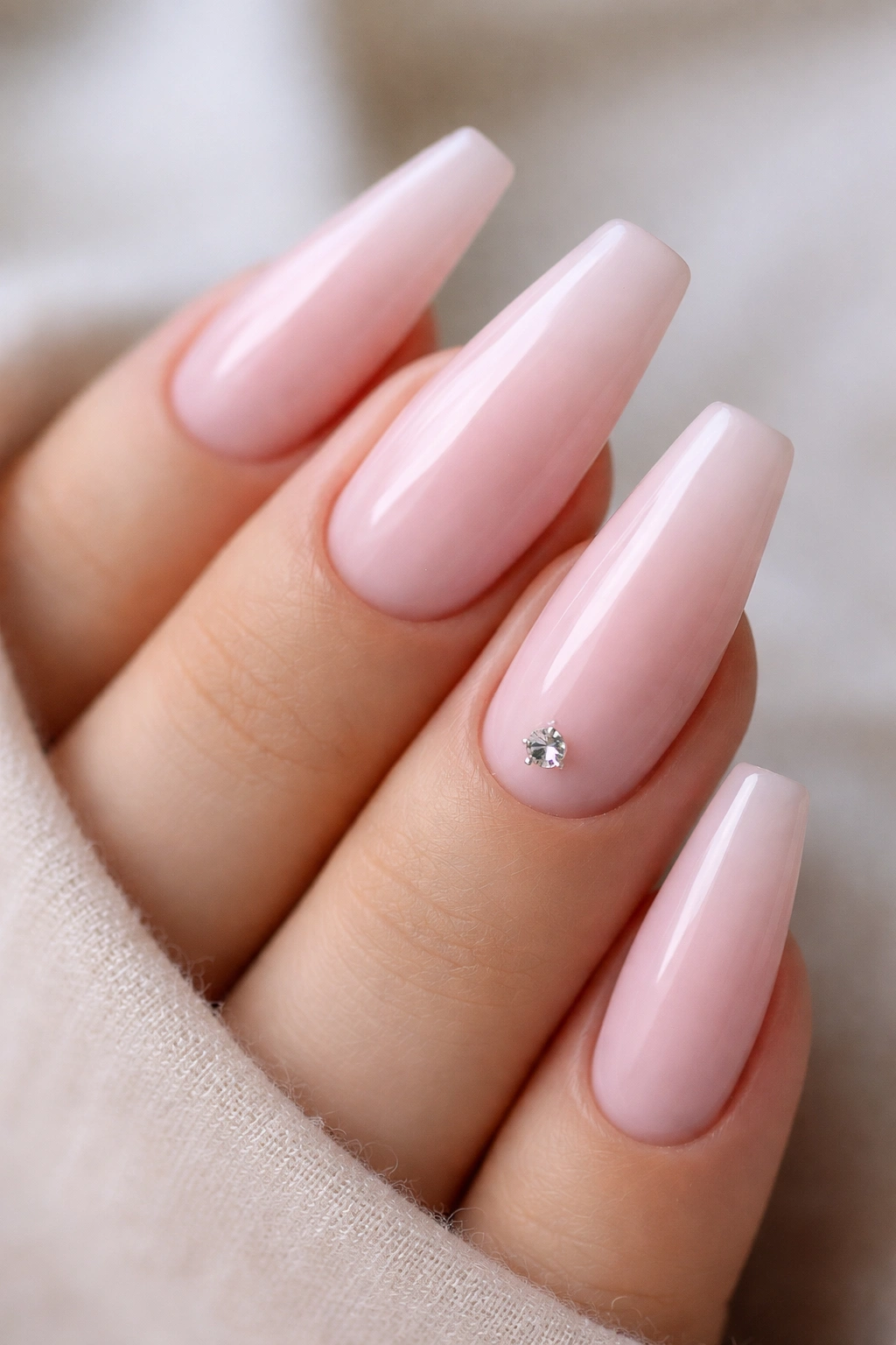 Milky pink nails with a single small crystal accent on one nail