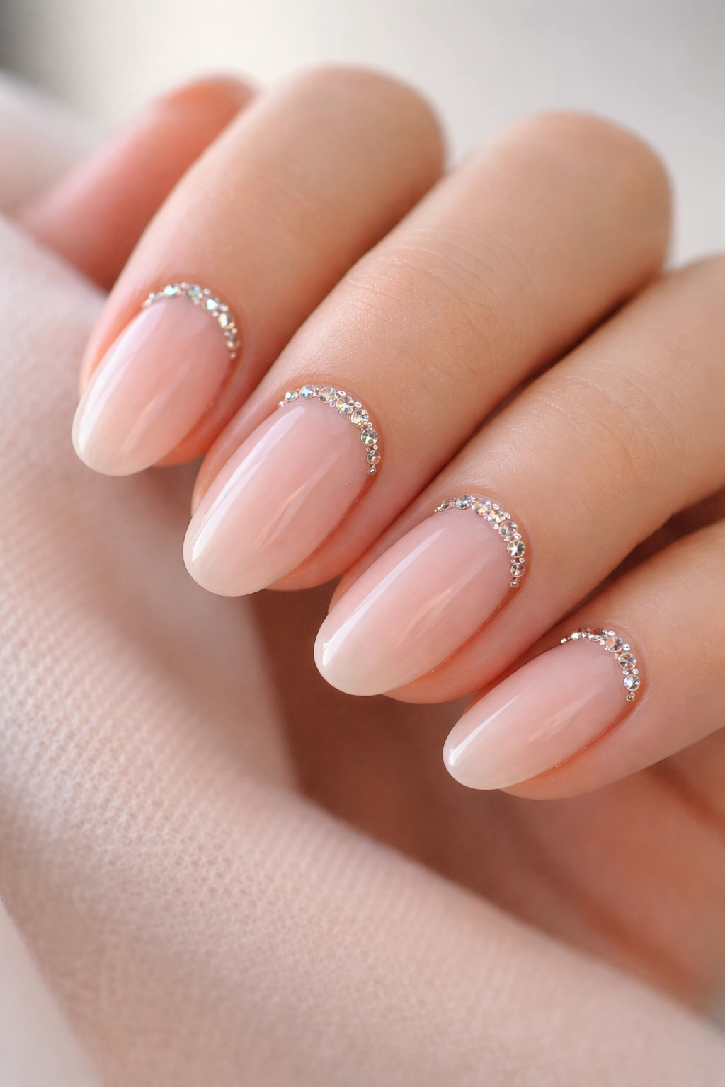 Close-up of milky pink nails with crystal-cuticle accents