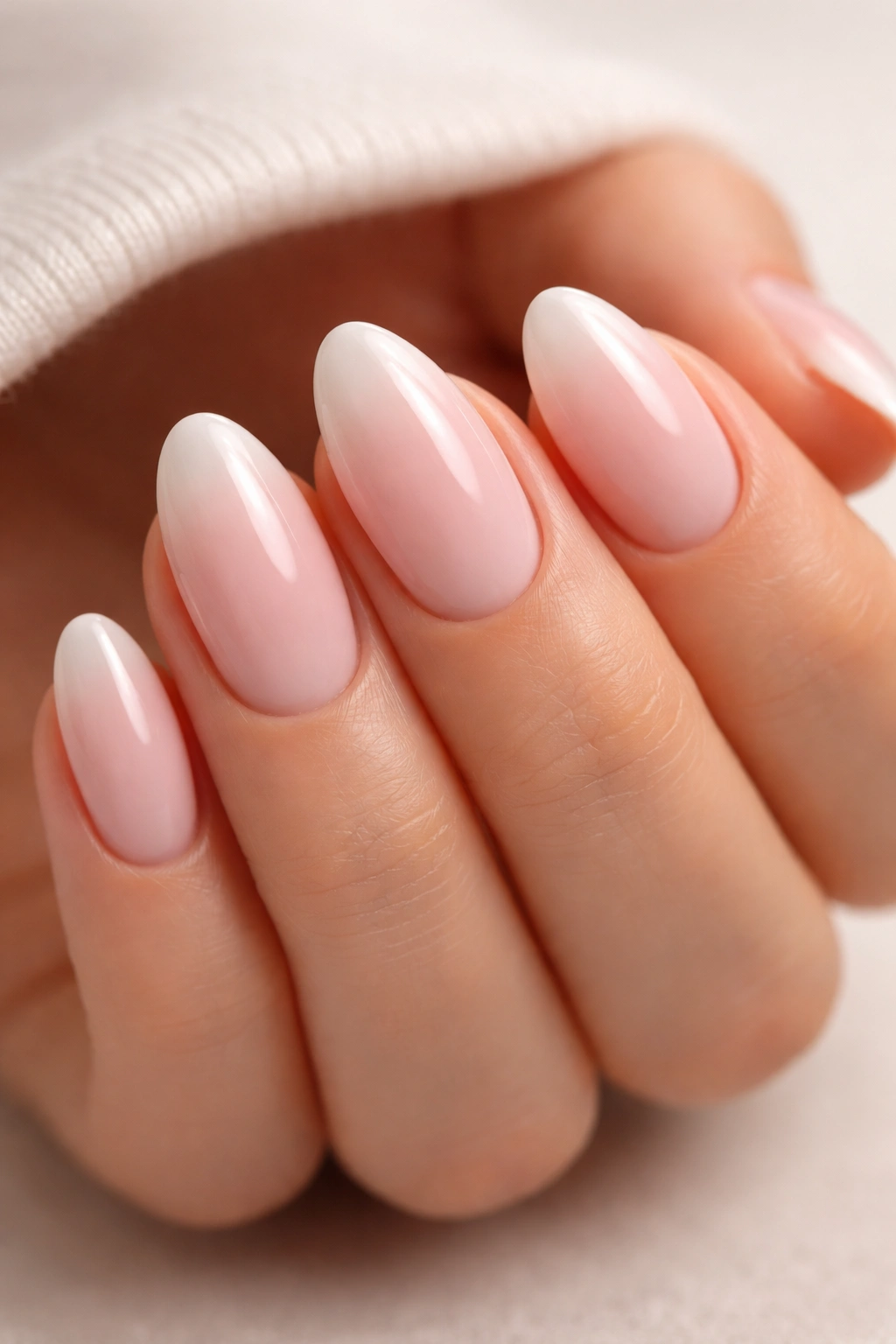 Close-up of short almond nails with milky pink to soft white dip powder ombre