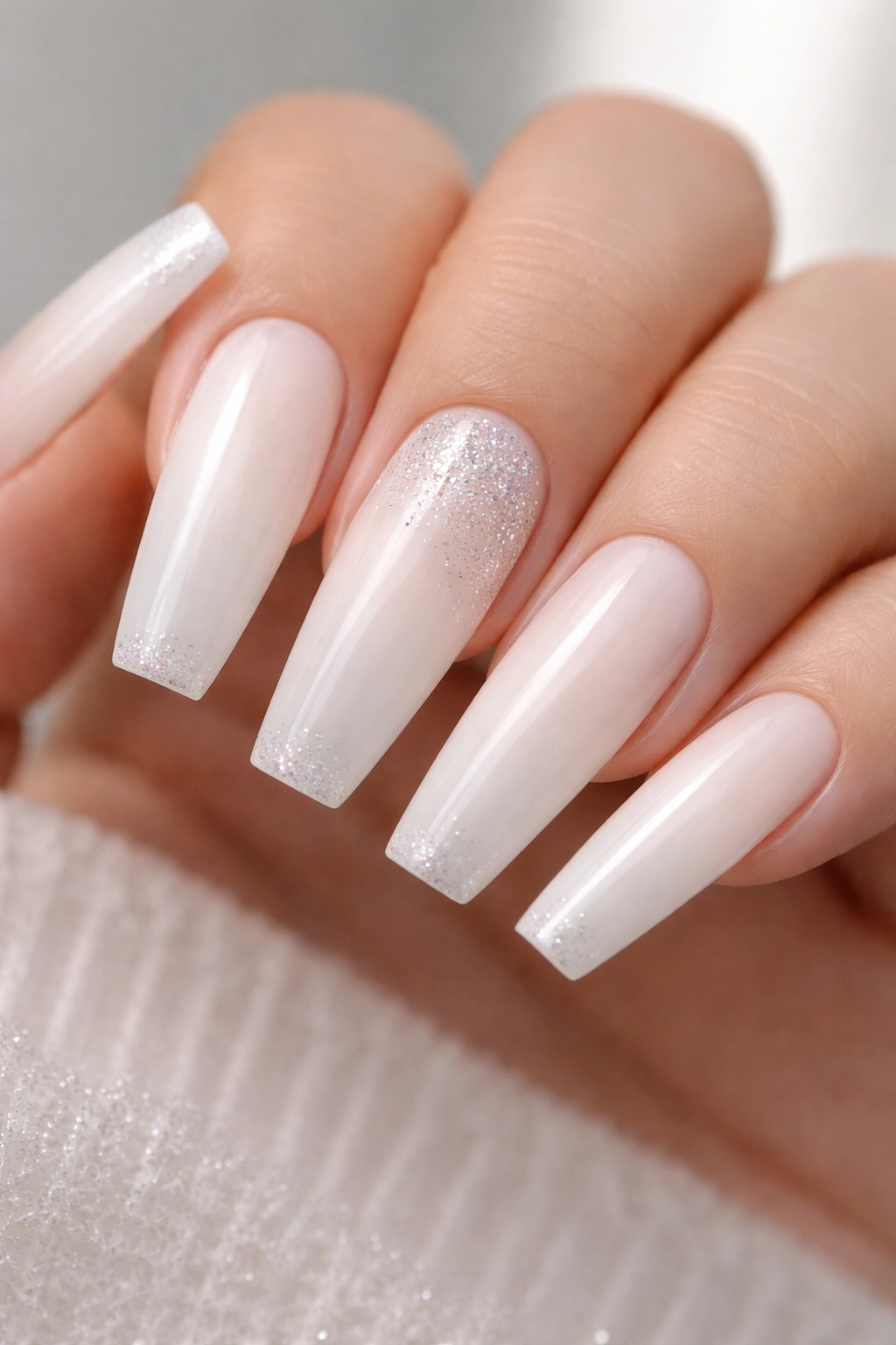 Milky white nails with subtle glitter placement on accent nail