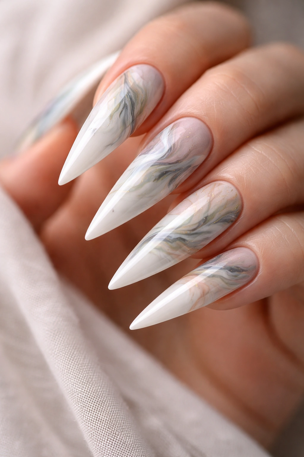 Milky white stiletto nails with marble and watercolor swirls in soft tones