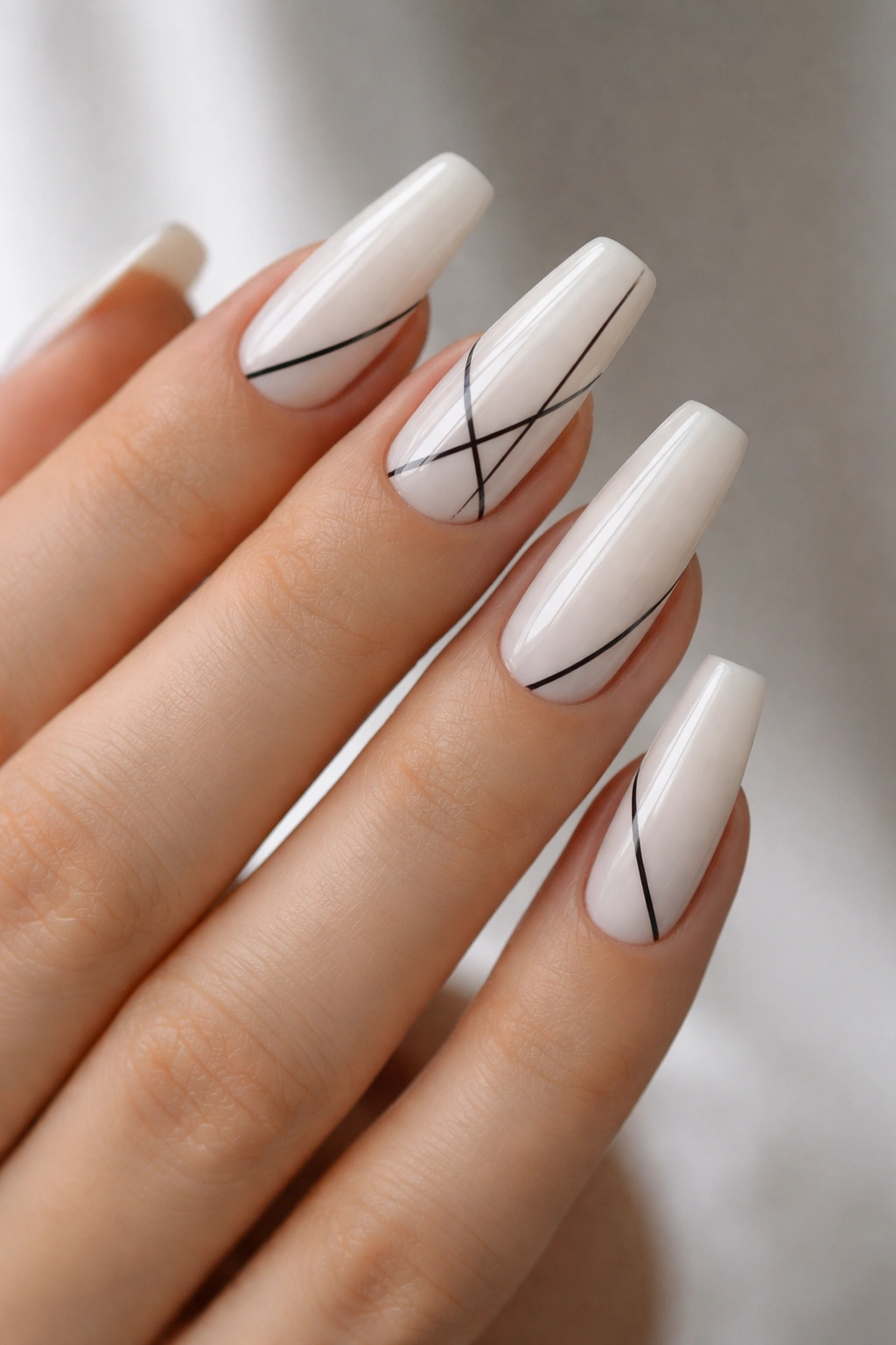 Milky white nails with thin black linear details in a minimalist pattern