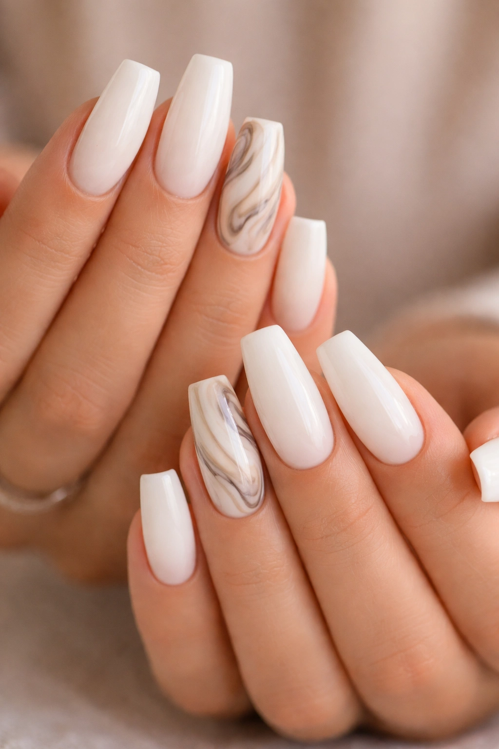 Milky white nails with a marbled accent nail featuring white, cream, gray, taupe swirls