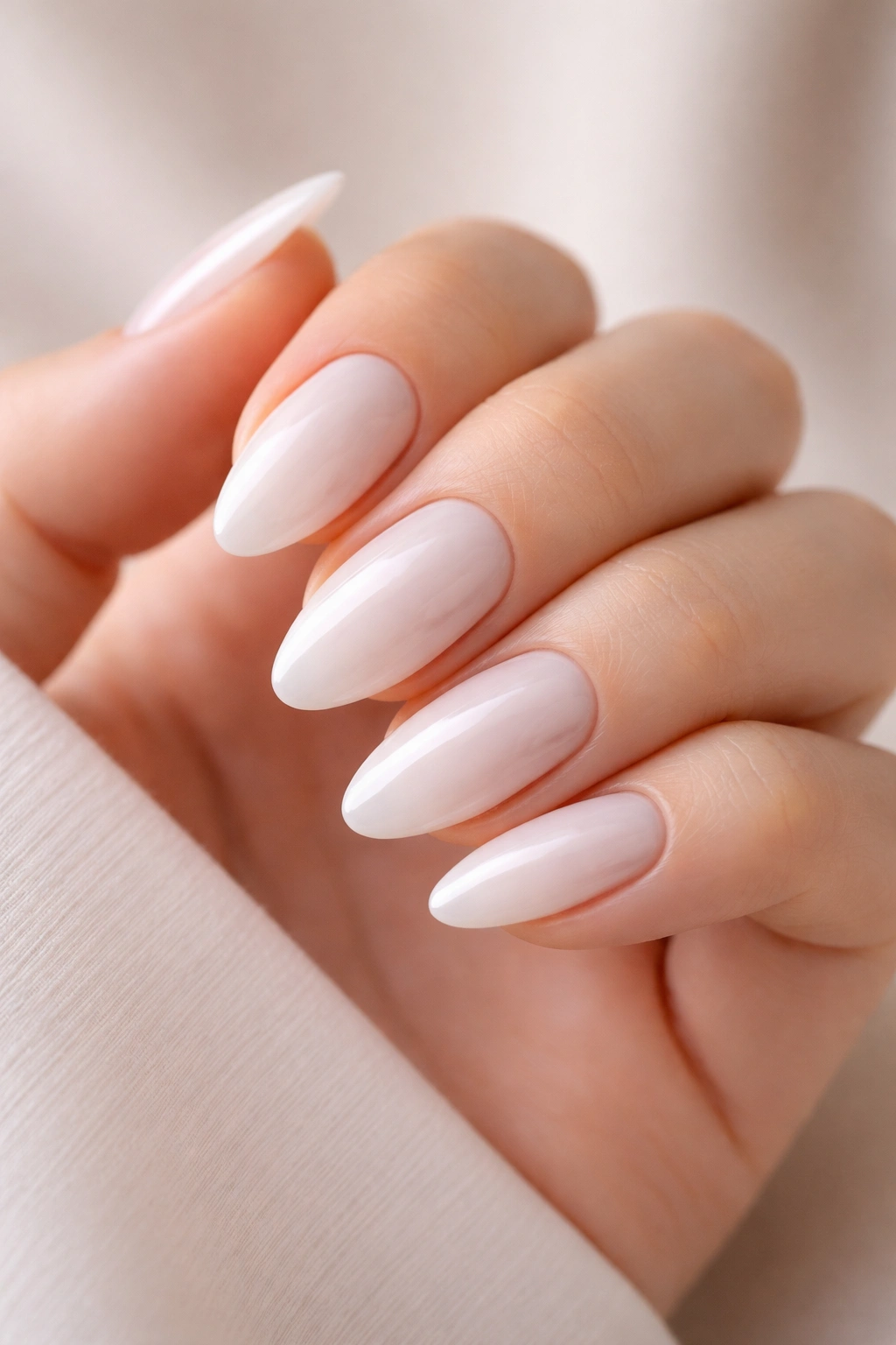 Close-up of milky white minimalist nails on almond shape with glossy finish
