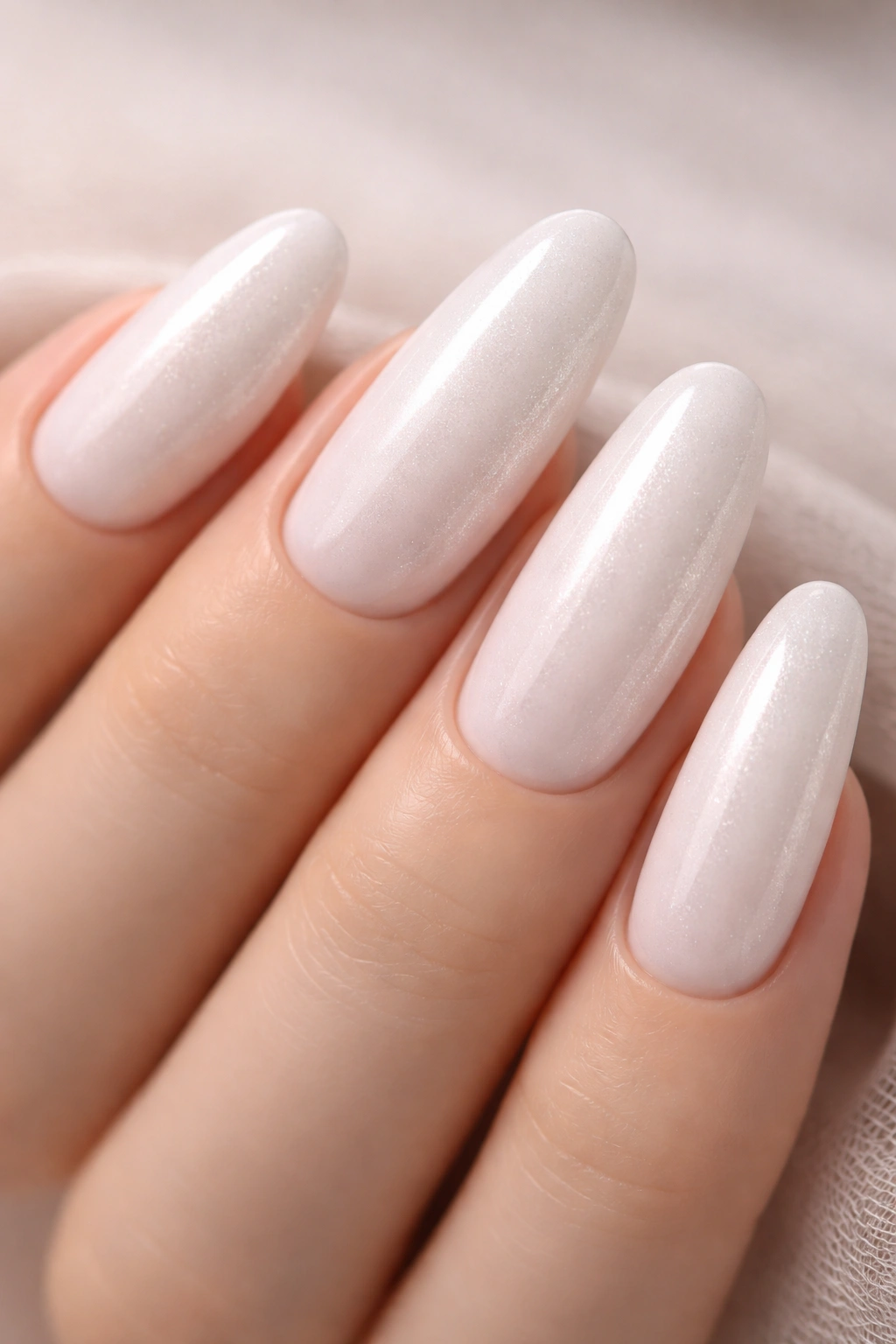 Close-up of milky white long oval nails with fine pearl shimmer